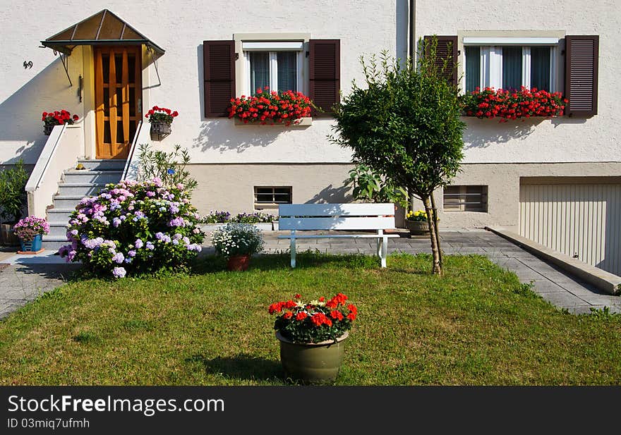 Beatiful yard with flowers and bench in front of the house. Beatiful yard with flowers and bench in front of the house