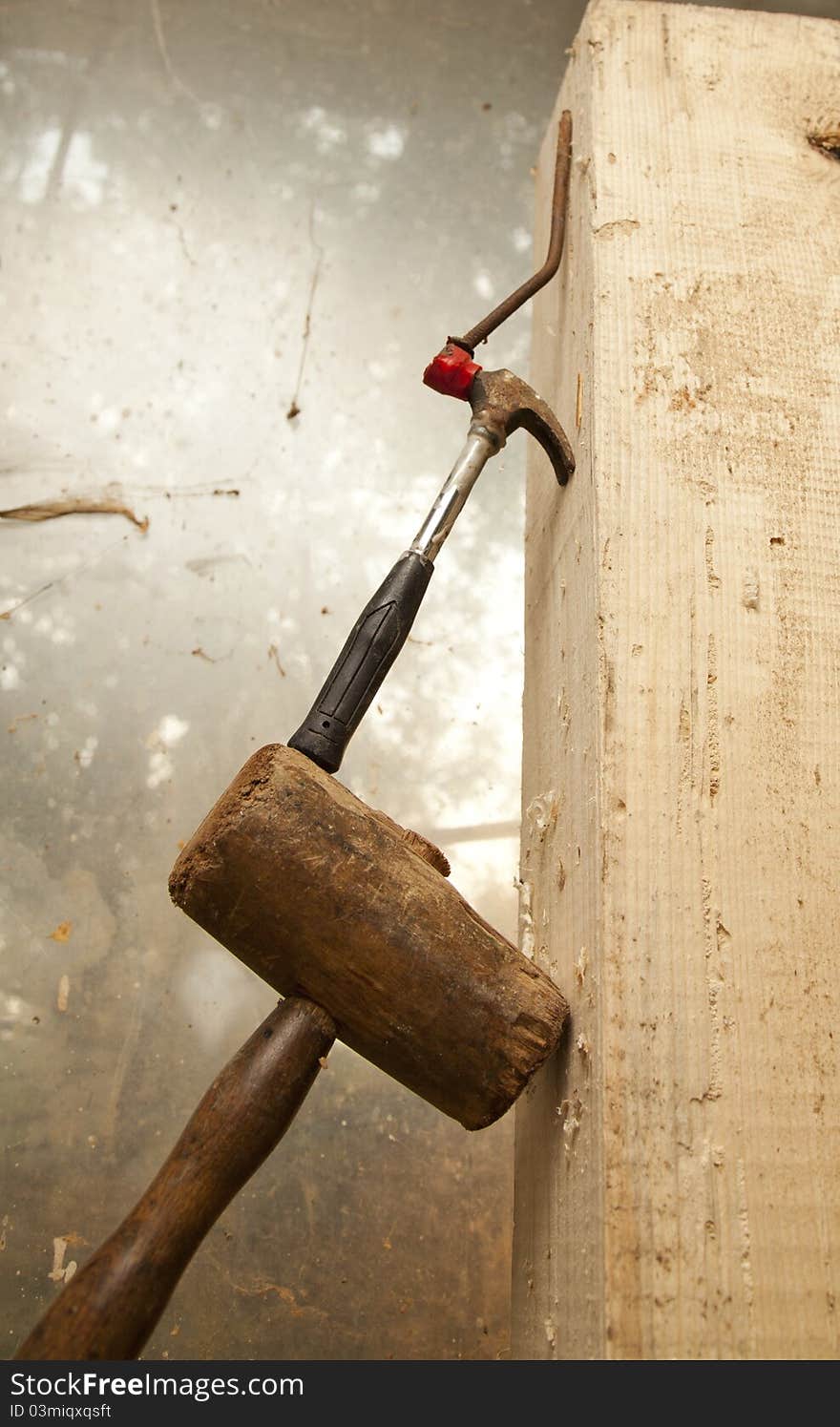 Hammer and nail on wood chunck on top of each other