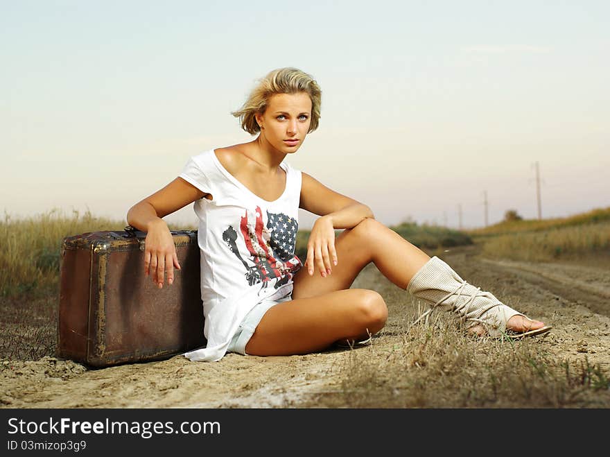 Pretty girl sitting on a suitcase