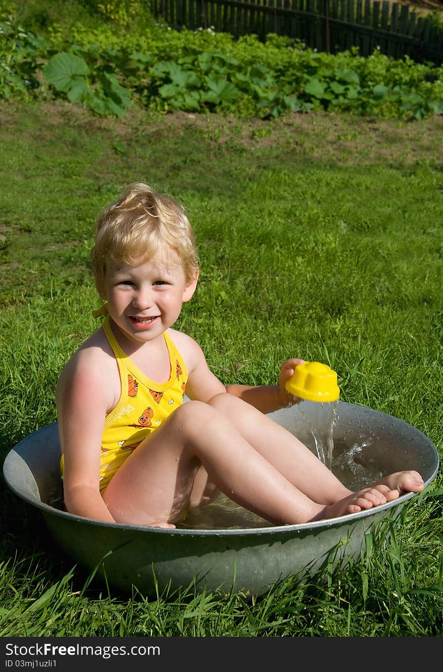 Girl in a yellow bathing suit bathing in pelvis. Girl in a yellow bathing suit bathing in pelvis