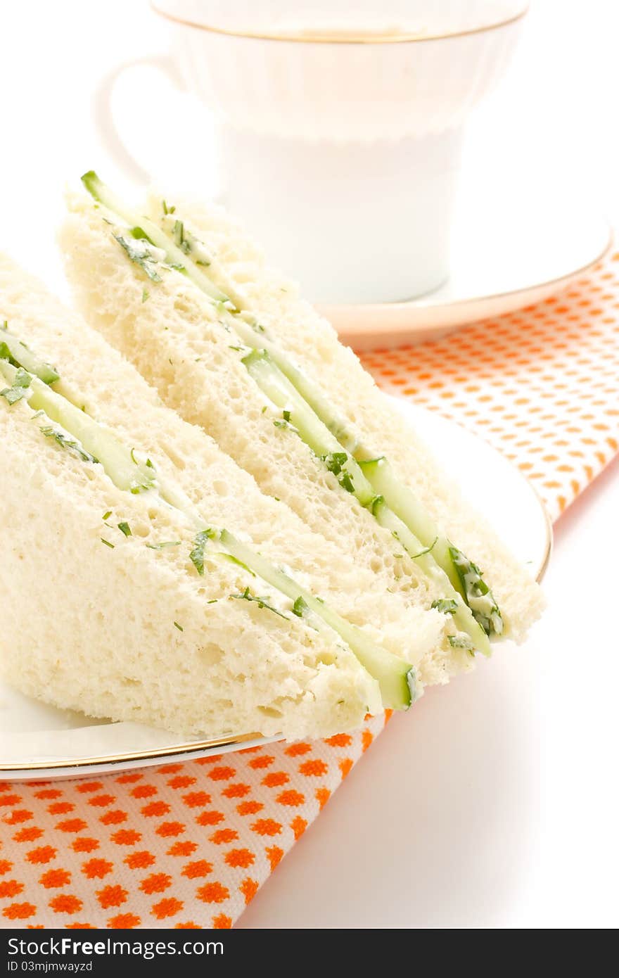 English sandwiches. Stuffing a cucumber, dill and butter. The shape is triangular. In the background is visible with a cup of tea. English sandwiches. Stuffing a cucumber, dill and butter. The shape is triangular. In the background is visible with a cup of tea.