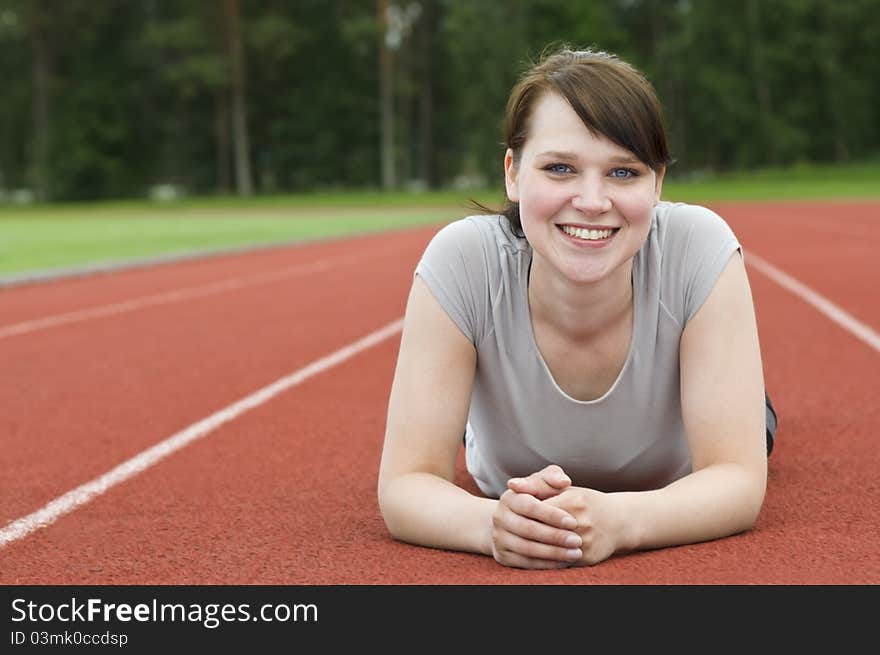 Young woman stretching on running track