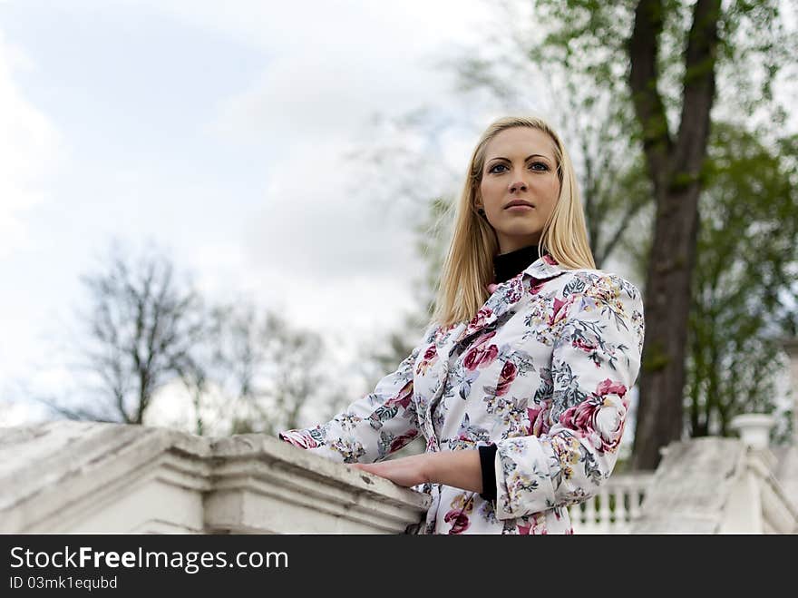 Blonde girl is leaning on old railing against the park. Blonde girl is leaning on old railing against the park