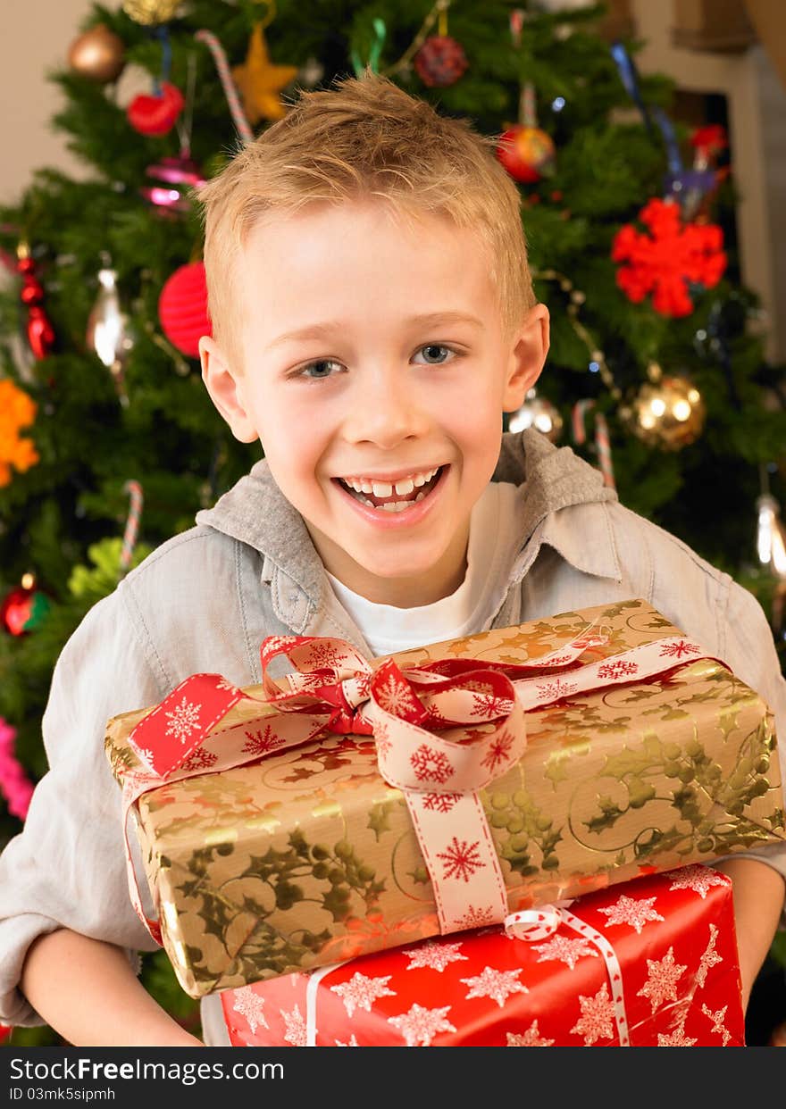 Young child holding gifts in front of Christmas tree