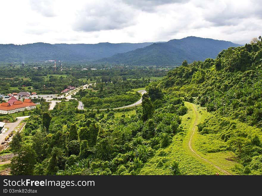 A pathway beside the hill cover with green grass. The way to Khun-Dan Prakarnchol Dam in Nakorn Nayok, Thailand. A pathway beside the hill cover with green grass. The way to Khun-Dan Prakarnchol Dam in Nakorn Nayok, Thailand