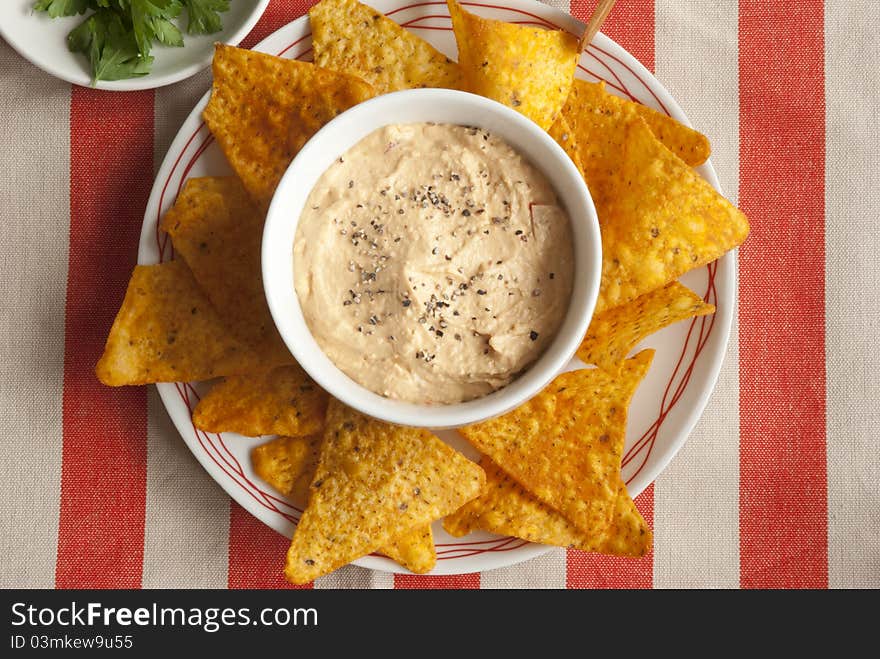 Chilli crisps with roasted red pepper houmous on a plate