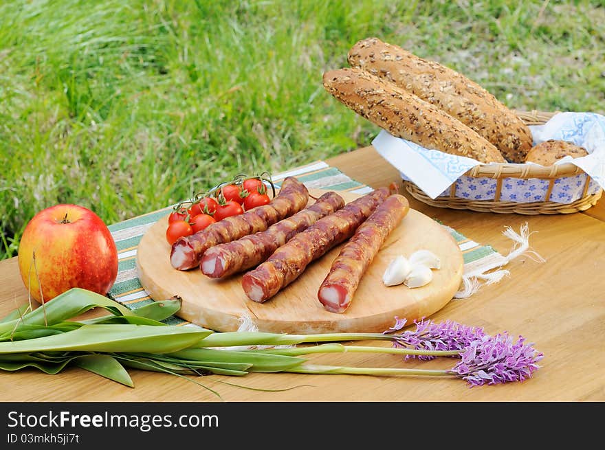 Domestic bread, tomatoes, sausage, apple, garlic in the nature. Domestic bread, tomatoes, sausage, apple, garlic in the nature