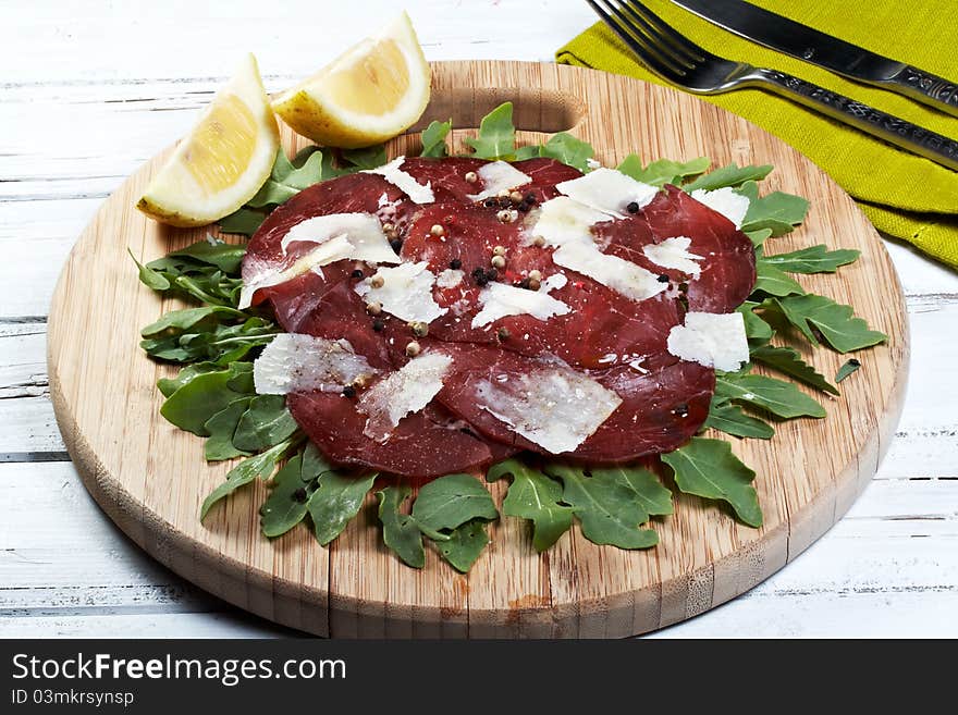 Italian bresaola seasoned with flakes parmesan, olive oil an pepper served on a bed of rocket