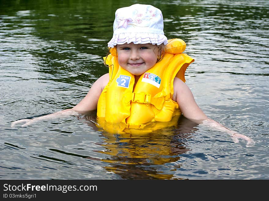 The child dressed in a life jacket studies to float. The child dressed in a life jacket studies to float