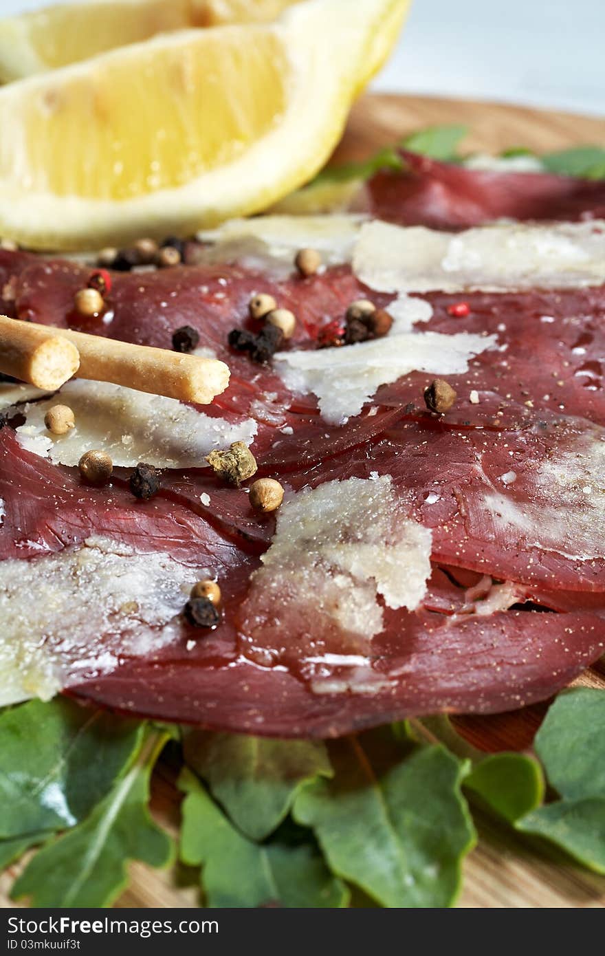 Italian bresaola seasoned with flakes parmesan, olive oil an pepper served on a bed of rocket