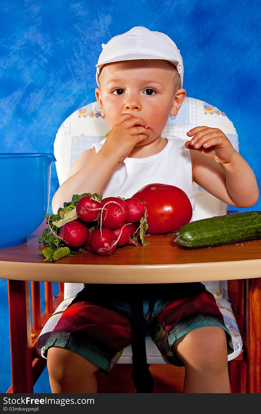 Short boy playing with vegetables against the blue mosaic background. Short boy playing with vegetables against the blue mosaic background