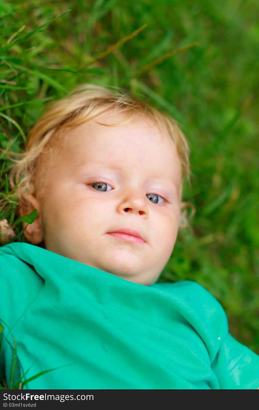 Baby with arrogant face expression laying on grass. Baby with arrogant face expression laying on grass