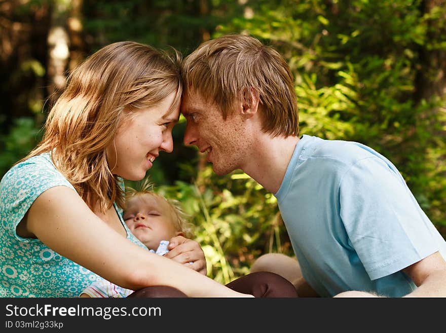 Happy family with mother holding sleeping baby enjoying being together in summer nature. Happy family with mother holding sleeping baby enjoying being together in summer nature