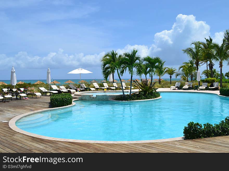 A pool with the water a beautiful turquoise with palm trees and lounge chairs surrounding. A pool with the water a beautiful turquoise with palm trees and lounge chairs surrounding