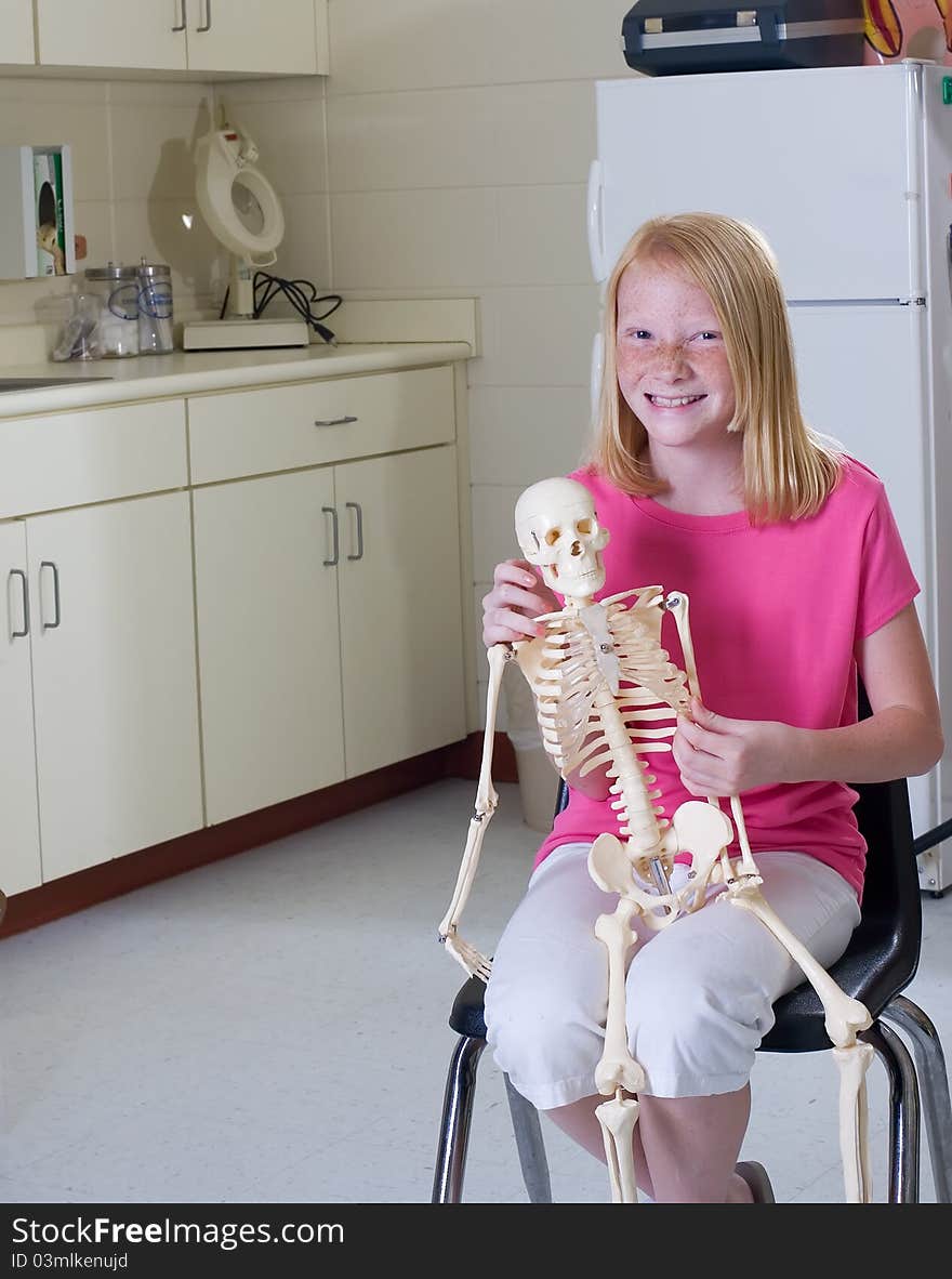 Young girl holding medical skeleton in pediatric office