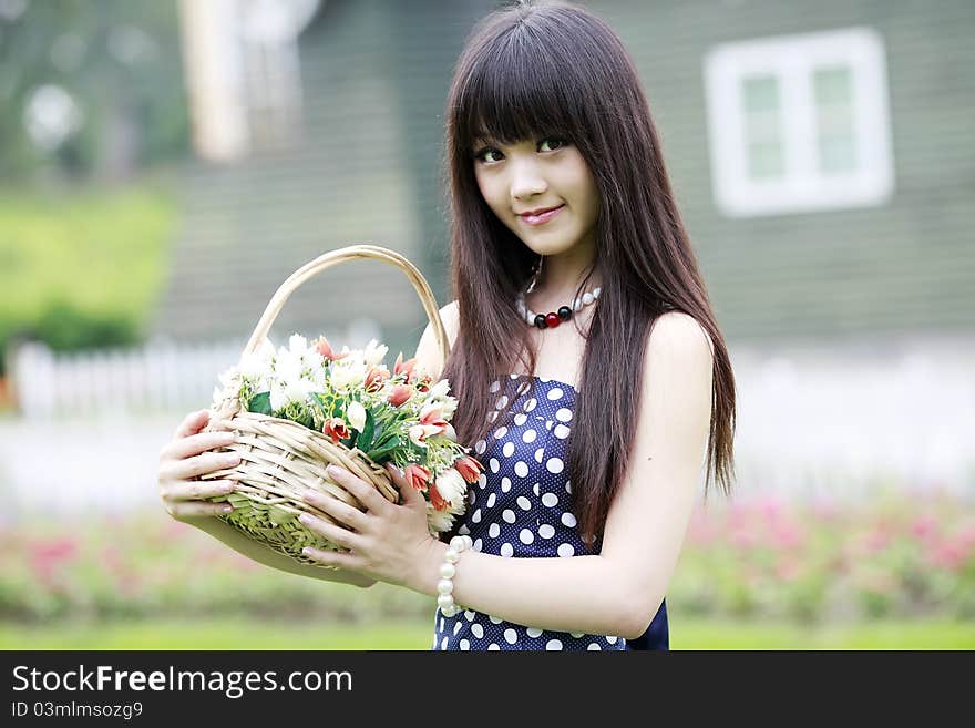 Attractive Asian girl holding a basket of flowers outdoor portrait. Attractive Asian girl holding a basket of flowers outdoor portrait.