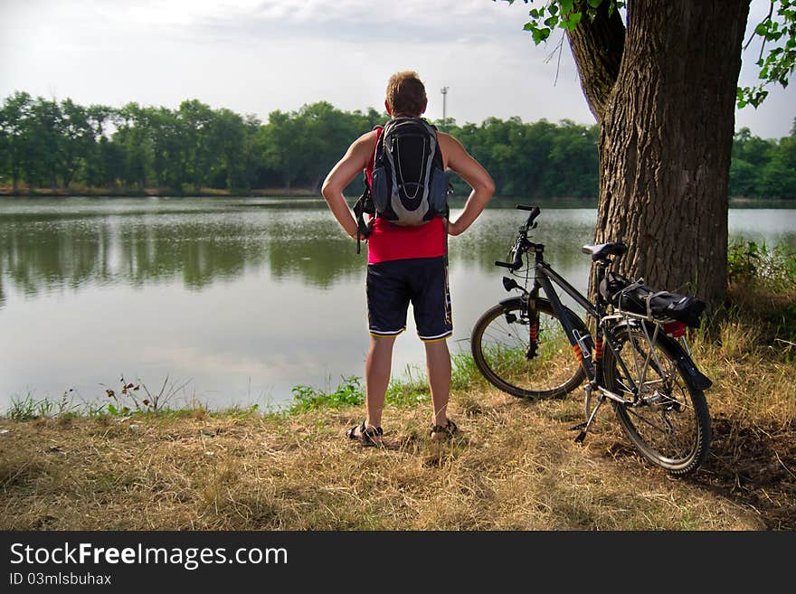 Camper man staying on shore of the lake near the bicycle