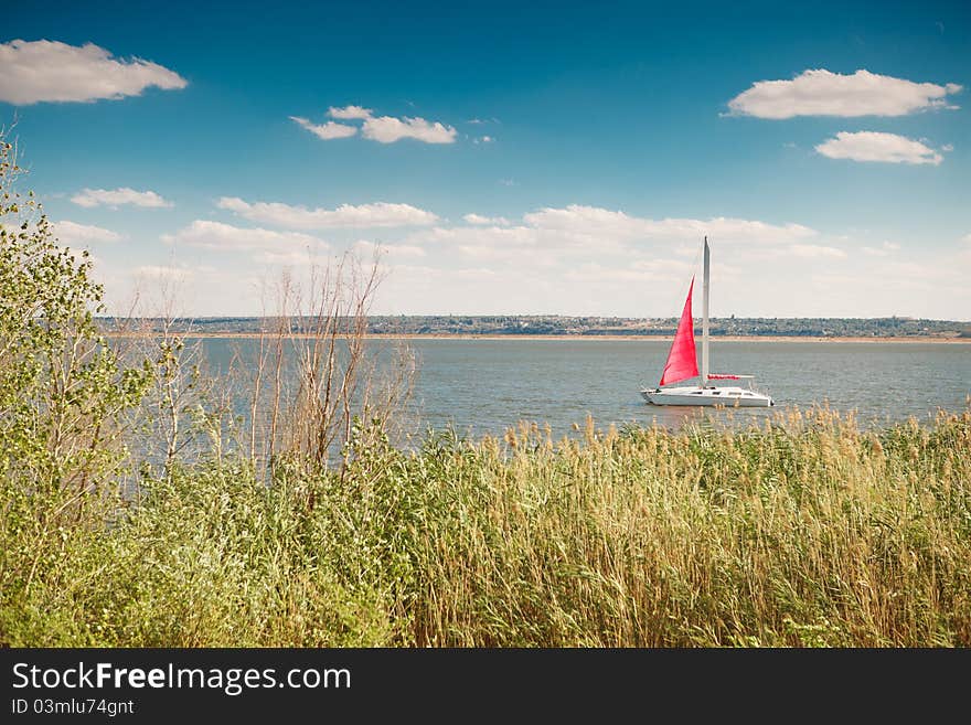 Boat under the red sail in the sea