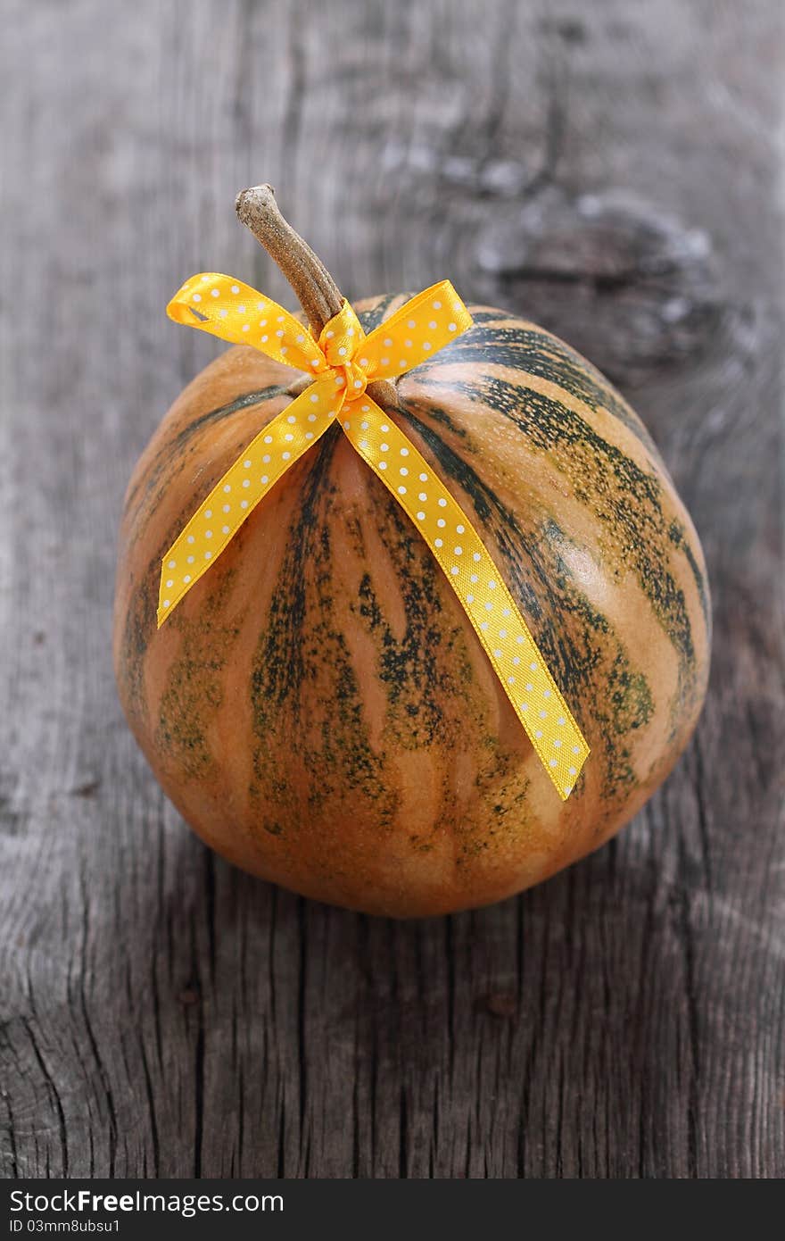 Pumpkin decorated with ribbon on the wooden background