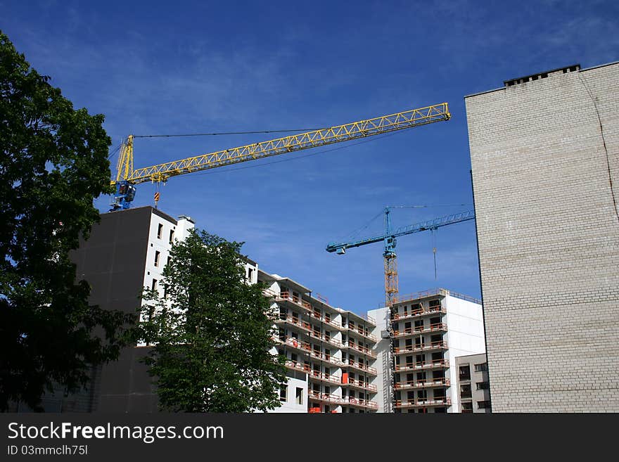 Building of the house by two tower cranes, blue and yellow