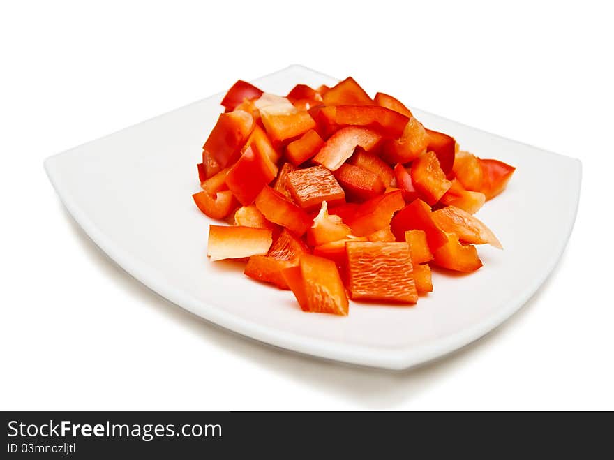 Slices of red sweet paprica on white square plate on white. Slices of red sweet paprica on white square plate on white