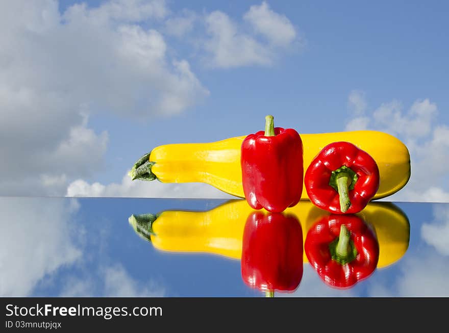 Two red peppers and courgette on mirror