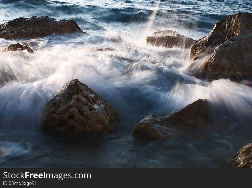 Stones in sea, waves of evening flow