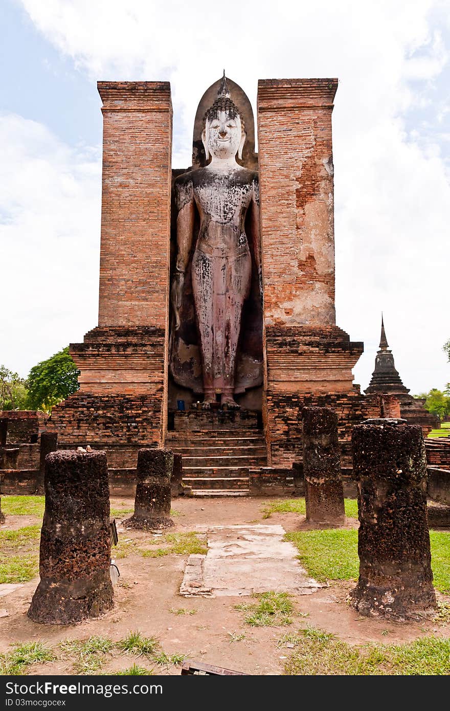 Standing Buddha statue behind pillars vertical