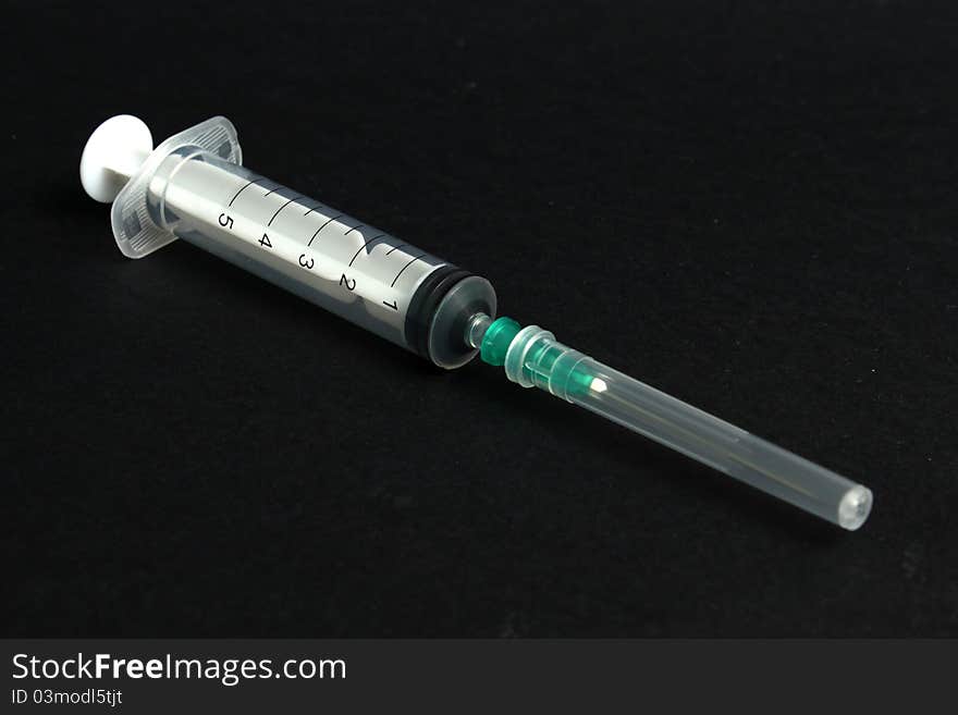 Packed syringe and needle with protector on black background