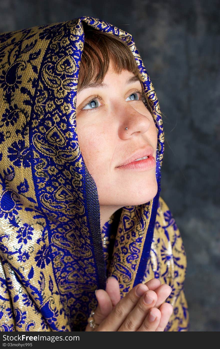 Portrait of a beautiful brown haired woman in profile, looking up as if in prayer, her head is wrapped in an exotic shawl and she looks pleased or happy. Portrait of a beautiful brown haired woman in profile, looking up as if in prayer, her head is wrapped in an exotic shawl and she looks pleased or happy.