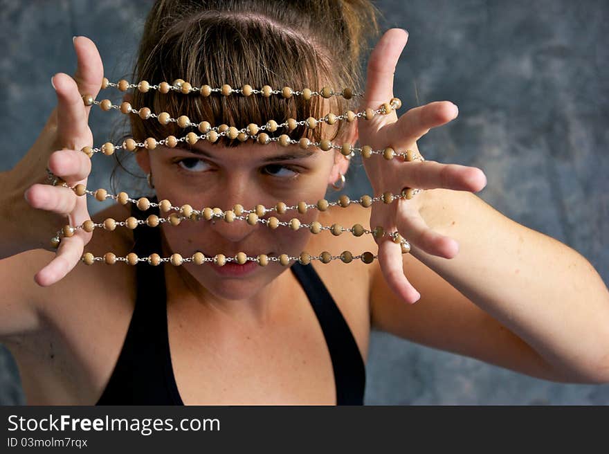 A young brown haired woman with serious look on face and playing children's game cat's cradle with a string of mala beads. A young brown haired woman with serious look on face and playing children's game cat's cradle with a string of mala beads.