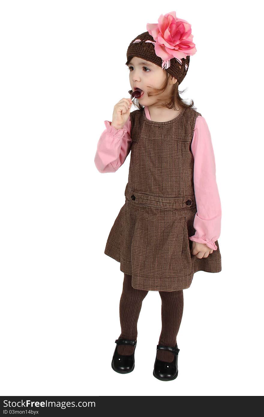 Cute brunette toddler earing a lollipop against white background. Cute brunette toddler earing a lollipop against white background