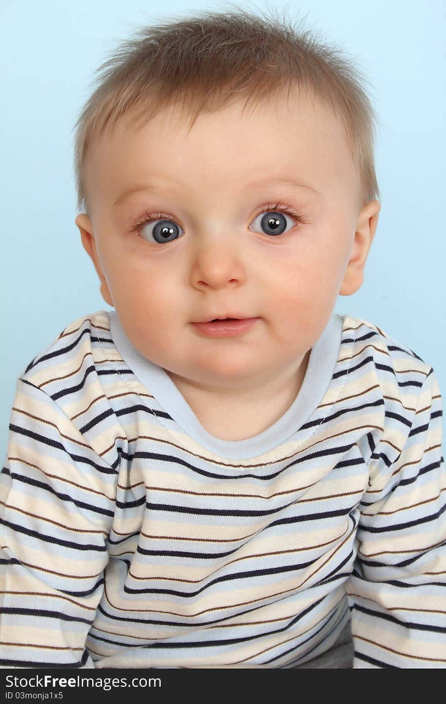 Surprized looking baby boy against a blue background. Surprized looking baby boy against a blue background