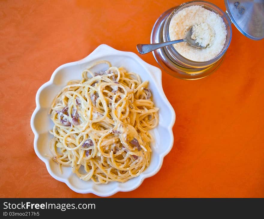 Plate with spaghetti alla carbonara and grated cheese