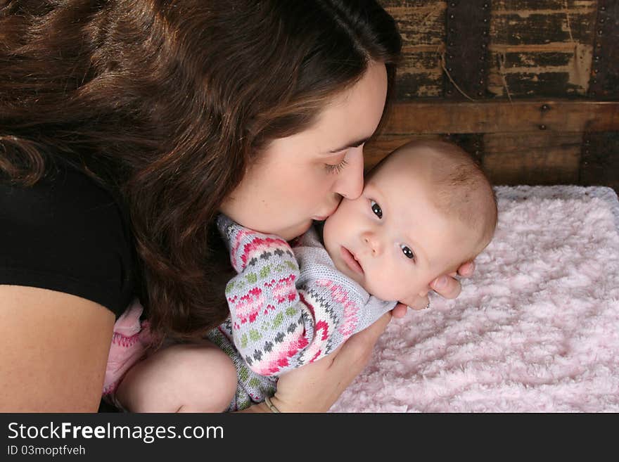 Brunette mother lovingly holding her baby girl. Brunette mother lovingly holding her baby girl