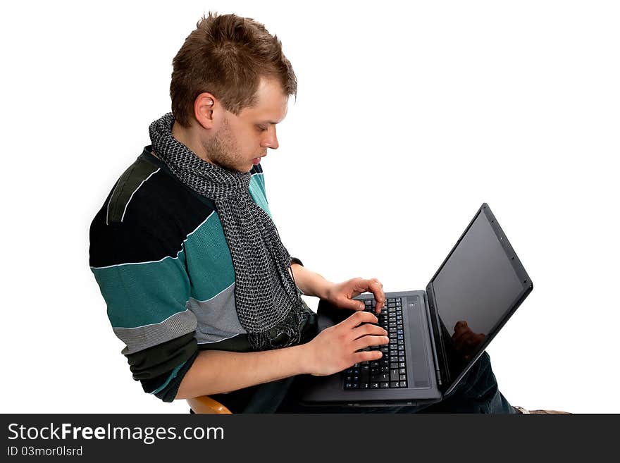 Young man with laptop sitting poses in the studio on a white background