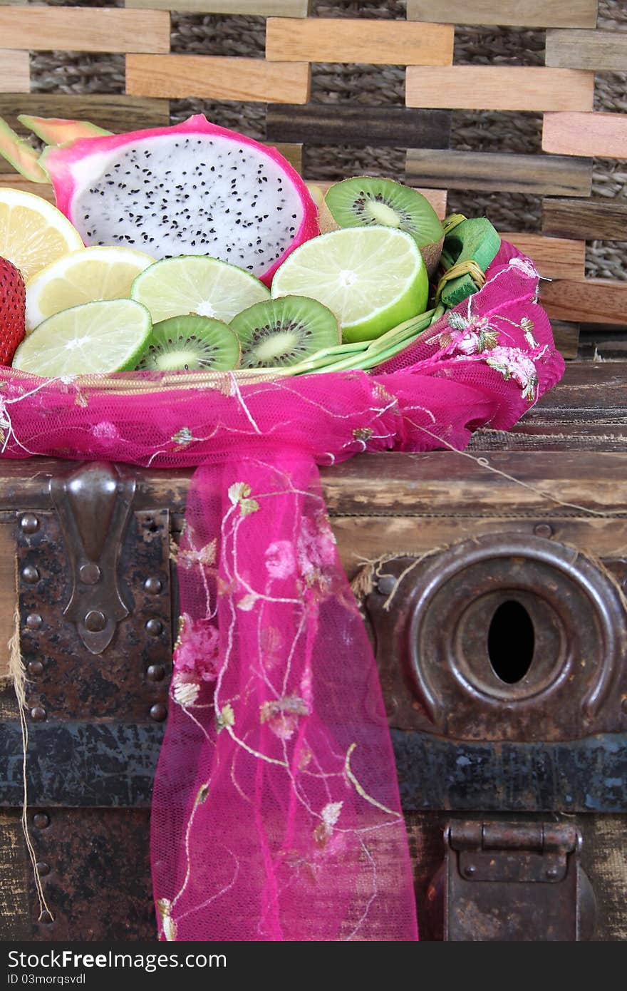 Fruit basket on an antique trunk with pink fabric