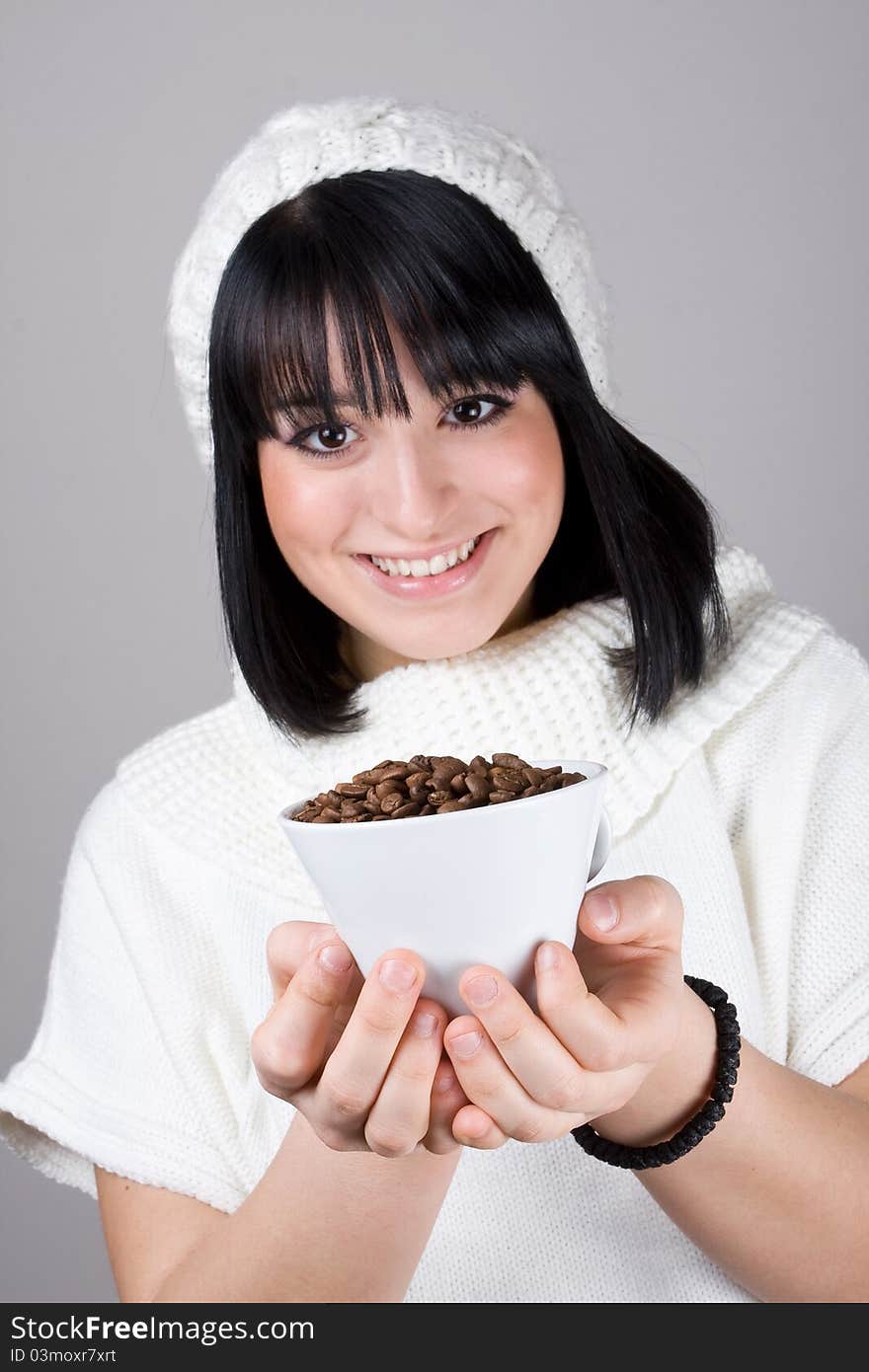 Beautiful young girl is holding a big white cup with coffee grains