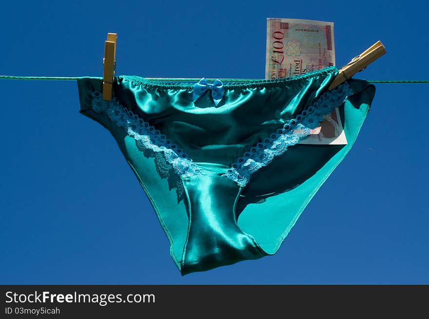 Silk and lace panties with a one hundred pound note sterling, on a respectable suburban washing line hinting at prostitution. Silk and lace panties with a one hundred pound note sterling, on a respectable suburban washing line hinting at prostitution.