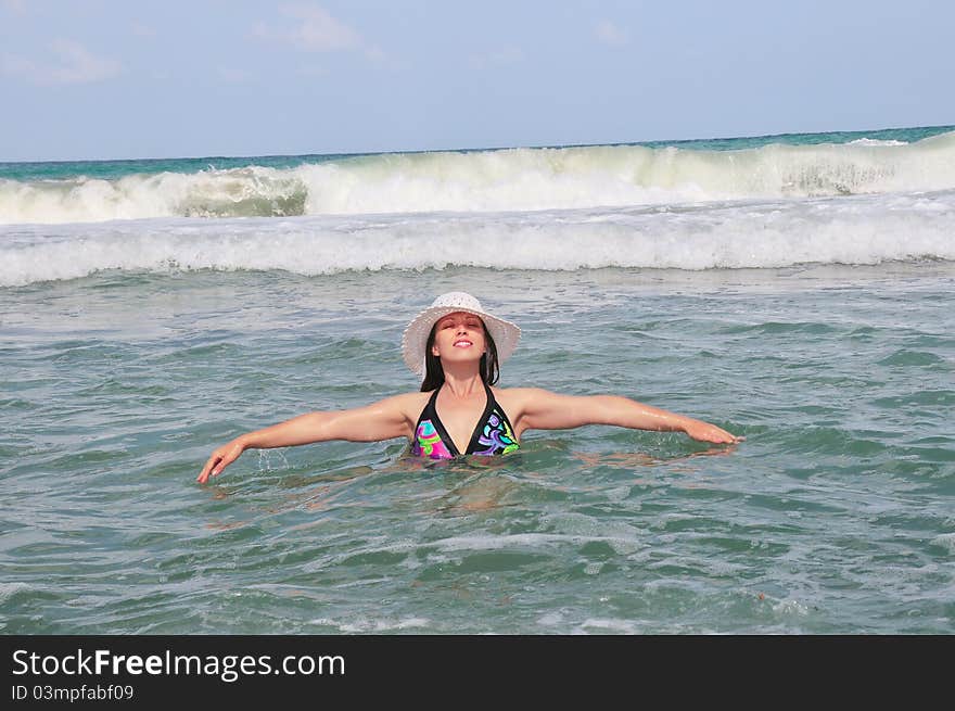 Girl standing in water, his arms and behind her a big wave is coming. Girl standing in water, his arms and behind her a big wave is coming