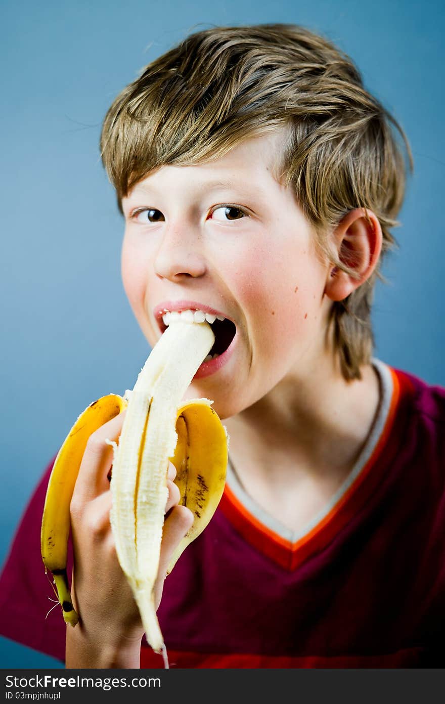 Teenager eating and holding a banana. Teenager eating and holding a banana.