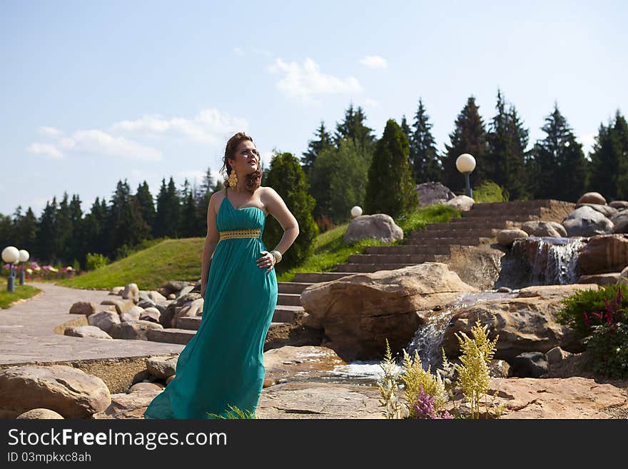 Beautiful brunette walking in the park next to a small waterfall