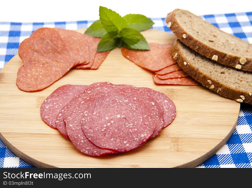 Salami with bread on edge board with mint