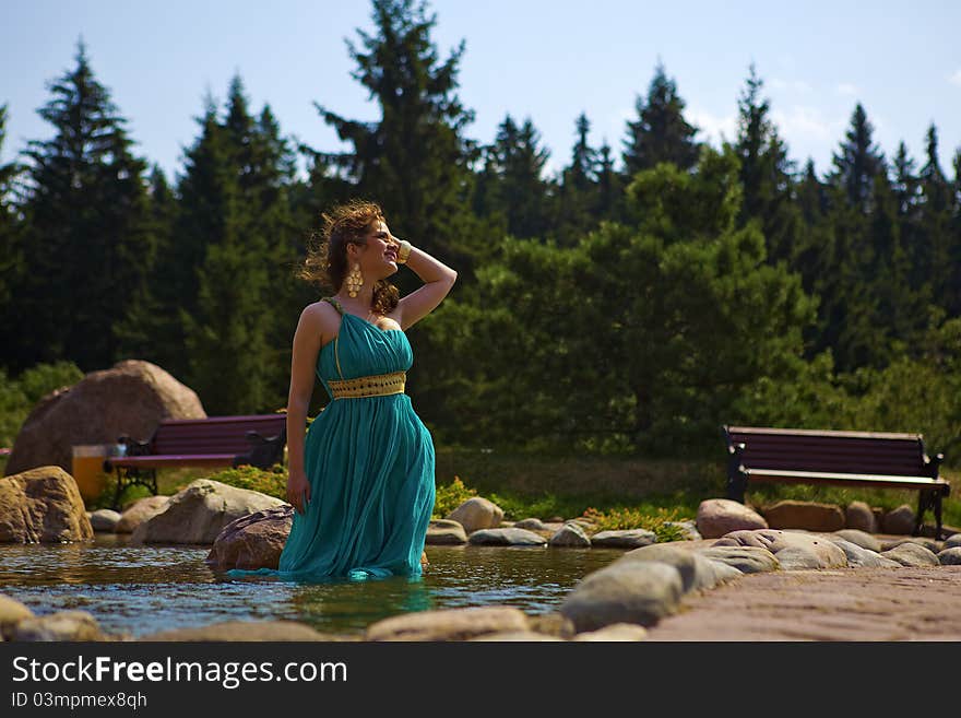 Beautiful brunette walking in the park next to a small waterfall