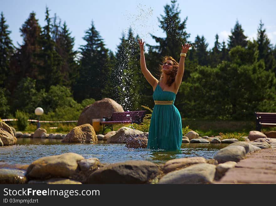 Beautiful brunette walking in the park next to a small waterfall