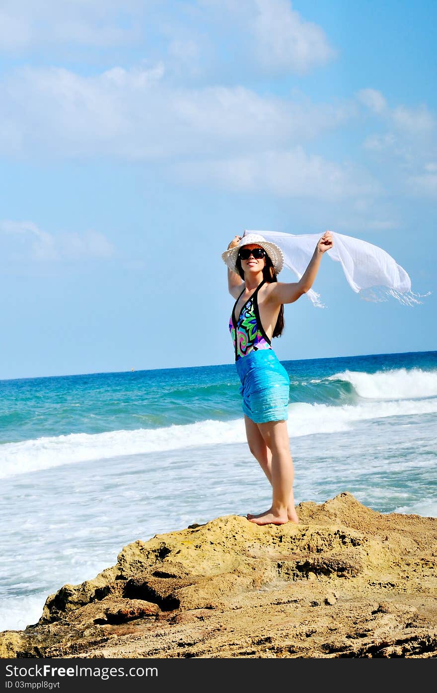 A girl stands on the beach and holding a white scarf that develops in the wind. A girl stands on the beach and holding a white scarf that develops in the wind