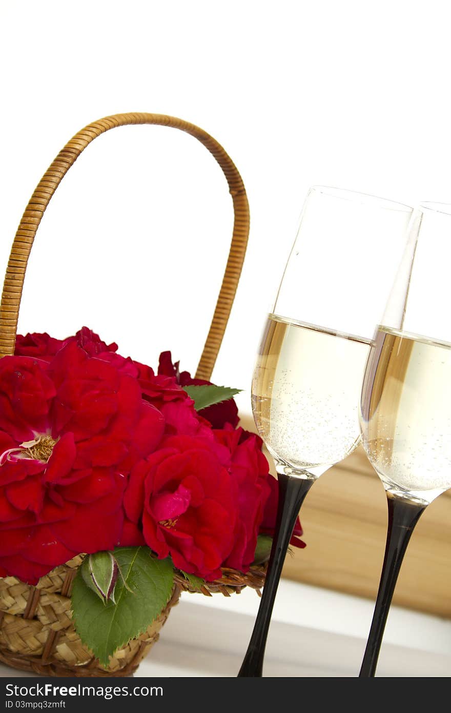 Beautiful basket full of red roses next to two glasses of champagne. isolated. Beautiful basket full of red roses next to two glasses of champagne. isolated