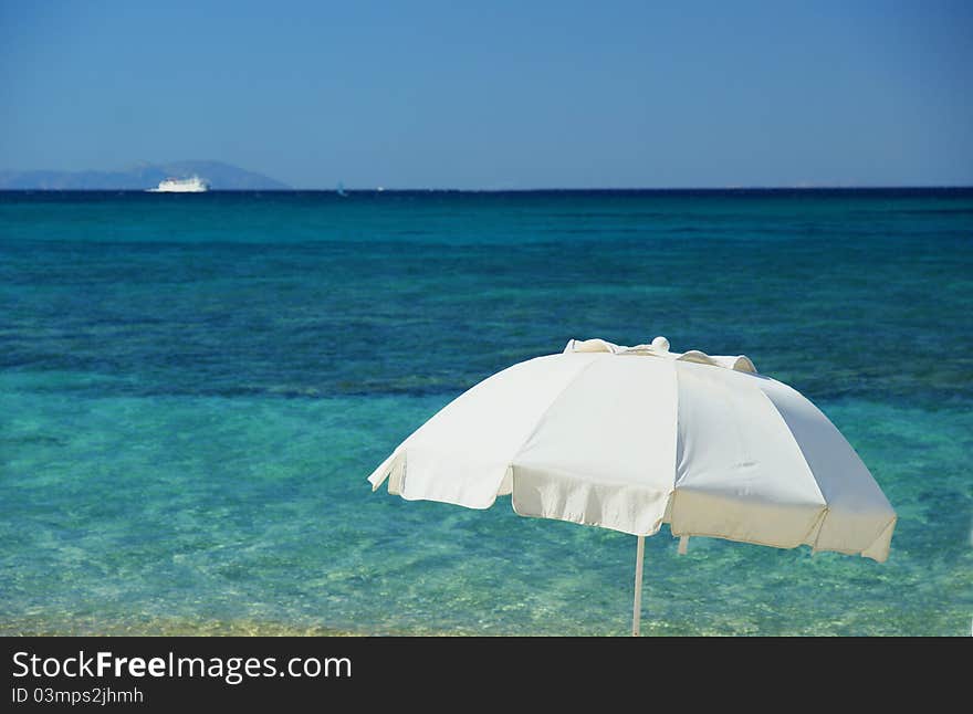 The Mediterranean beach whit white umbrella and boat.