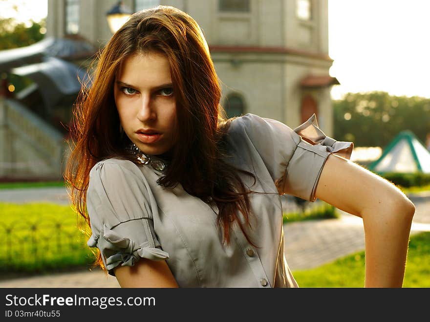 Portrait of a beautiful girl posing at the city street in sunset back light