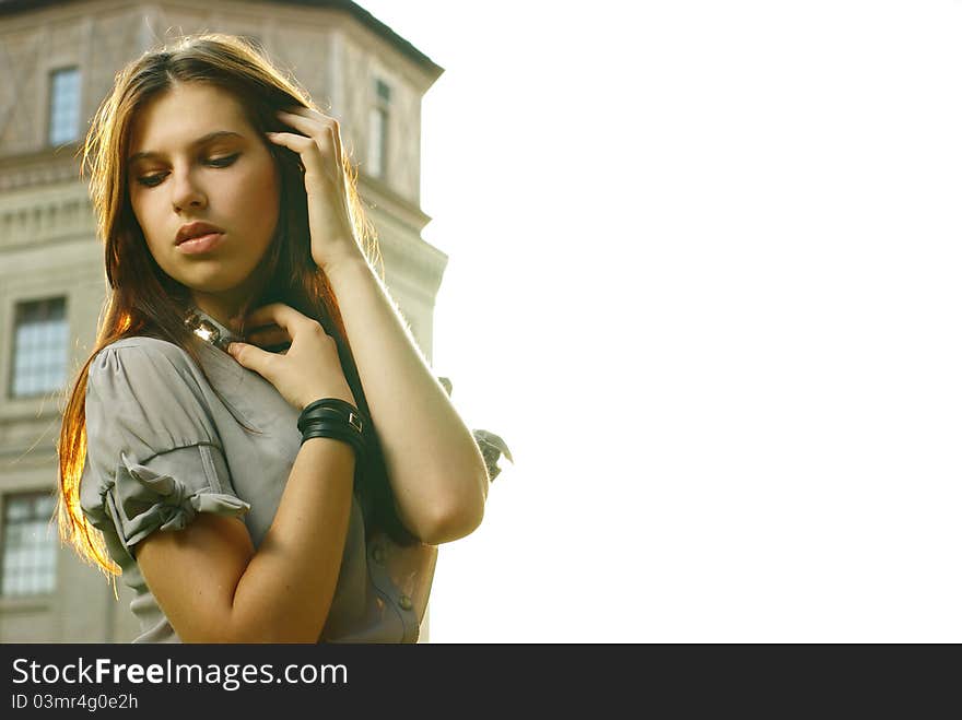 Portrait of a beautiful girl posing at the city street in sunset back light